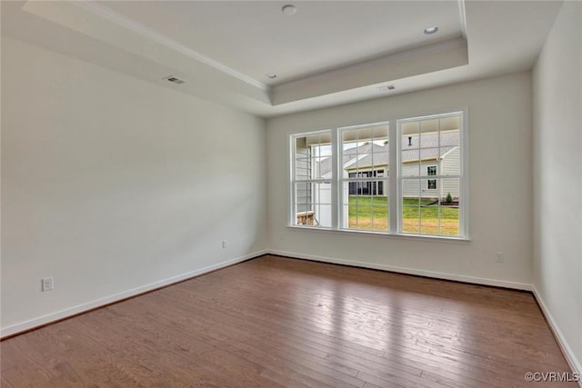 spare room with a tray ceiling, baseboards, dark wood-type flooring, and visible vents