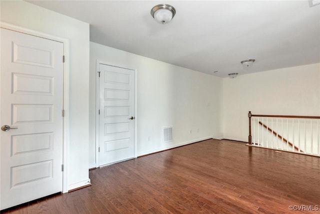 unfurnished room featuring visible vents, baseboards, and dark wood-type flooring