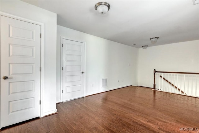 empty room featuring dark wood finished floors, visible vents, and baseboards