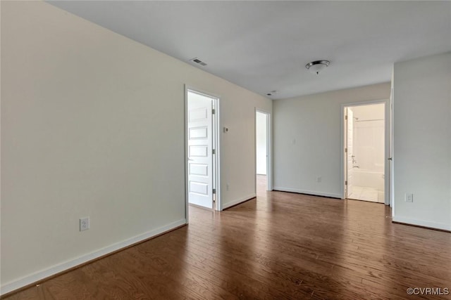 unfurnished room featuring wood finished floors, visible vents, and baseboards