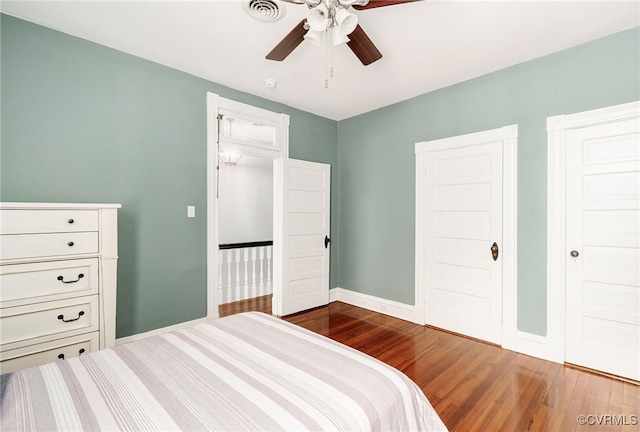 bedroom featuring dark wood-style floors, visible vents, ceiling fan, and baseboards