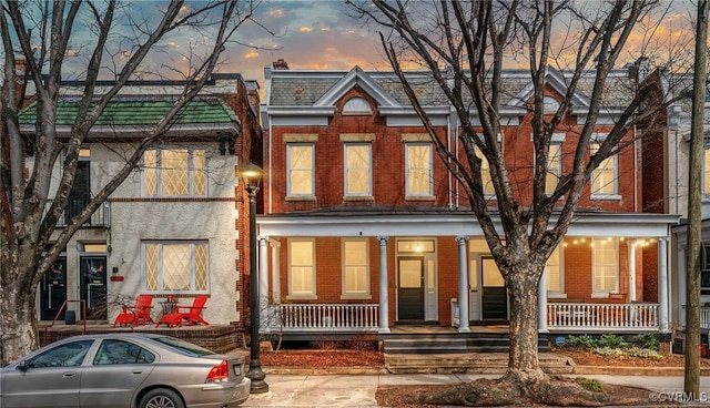 view of property featuring brick siding and a porch