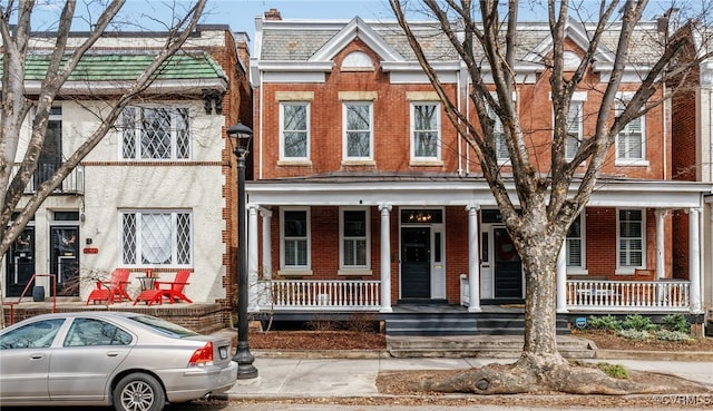 townhome / multi-family property featuring a porch and brick siding