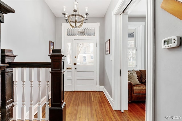 entryway featuring a notable chandelier, baseboards, and light wood-style floors