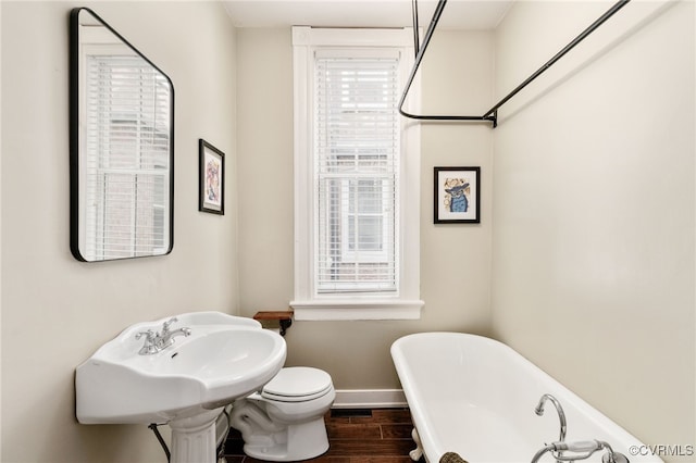 full bath with a freestanding tub, toilet, wood finished floors, and baseboards