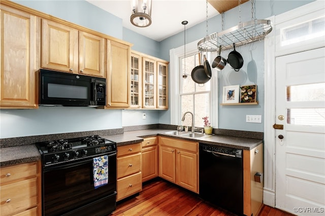 kitchen featuring dark countertops, light brown cabinets, glass insert cabinets, black appliances, and a sink