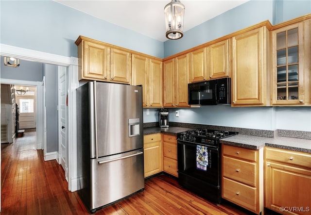 kitchen with dark countertops, black appliances, dark wood finished floors, and light brown cabinetry