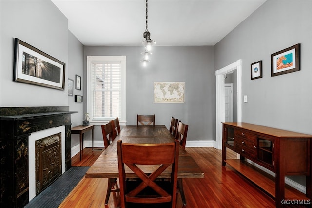 dining space with hardwood / wood-style floors, a fireplace with flush hearth, and baseboards