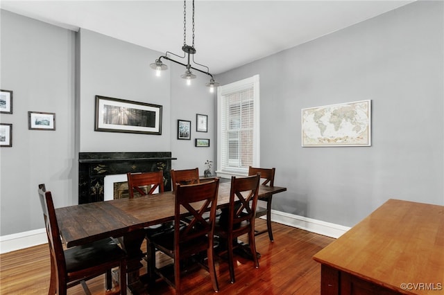 dining space with a fireplace, baseboards, and dark wood-style flooring