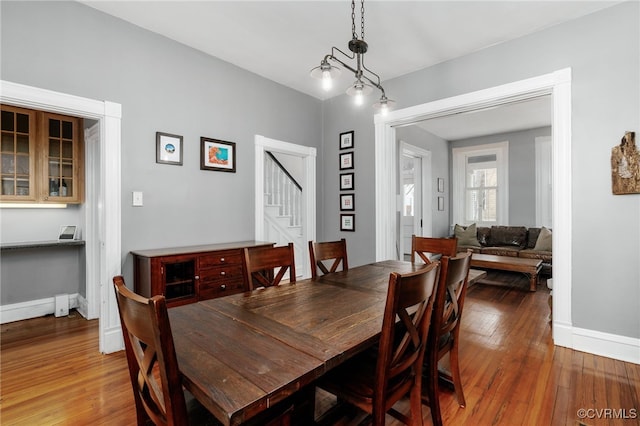 dining area featuring stairs, baseboards, and hardwood / wood-style flooring