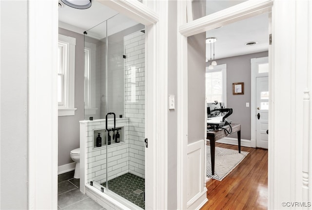 full bath featuring visible vents, a shower stall, toilet, and wood finished floors