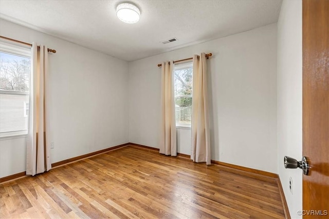 empty room with visible vents, baseboards, and light wood finished floors