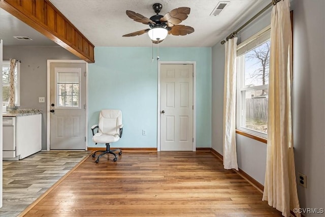 living area featuring light wood-type flooring, visible vents, and baseboards