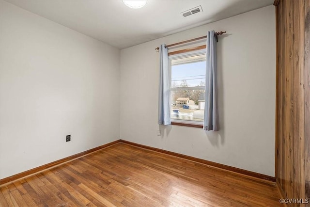 unfurnished room with wood finished floors, visible vents, and baseboards