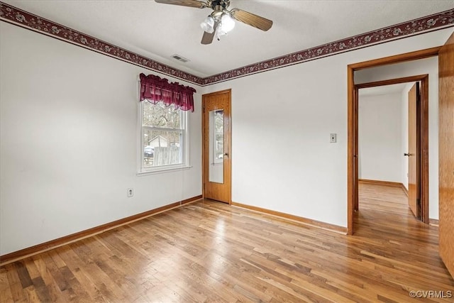 unfurnished room featuring a ceiling fan, baseboards, visible vents, and light wood finished floors