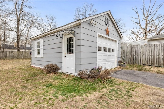 detached garage featuring fence and driveway