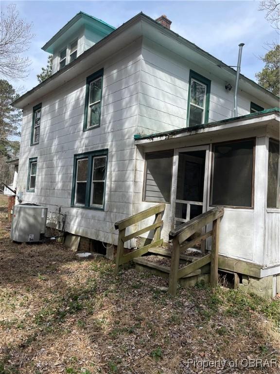 rear view of house with central AC unit and a sunroom