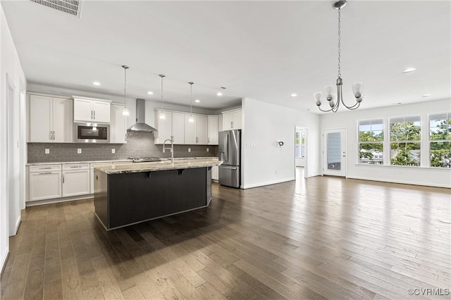 kitchen featuring visible vents, open floor plan, appliances with stainless steel finishes, dark wood-style floors, and wall chimney exhaust hood