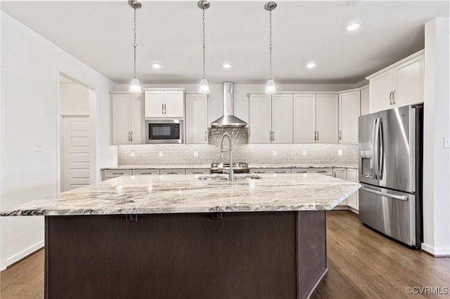 kitchen with dark wood-style flooring, a sink, appliances with stainless steel finishes, white cabinetry, and wall chimney exhaust hood