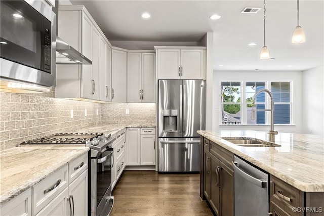 kitchen with visible vents, a sink, backsplash, dark wood finished floors, and appliances with stainless steel finishes