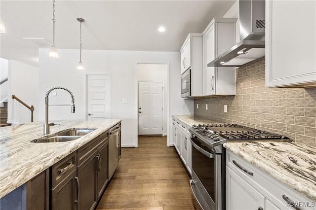 kitchen with tasteful backsplash, dark wood-type flooring, stainless steel appliances, wall chimney exhaust hood, and a sink