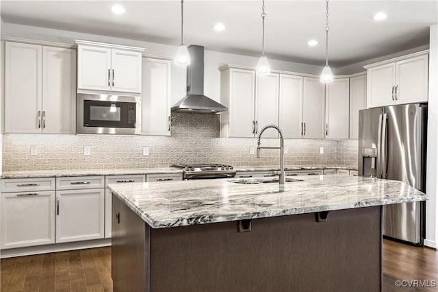 kitchen featuring built in microwave, a sink, wall chimney exhaust hood, range, and stainless steel fridge