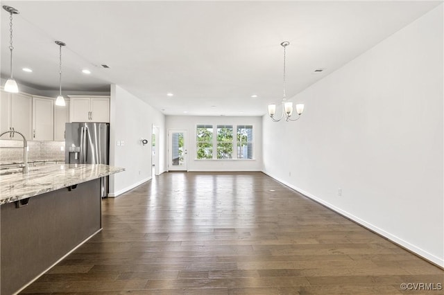 unfurnished living room with visible vents, baseboards, recessed lighting, dark wood-style floors, and a notable chandelier