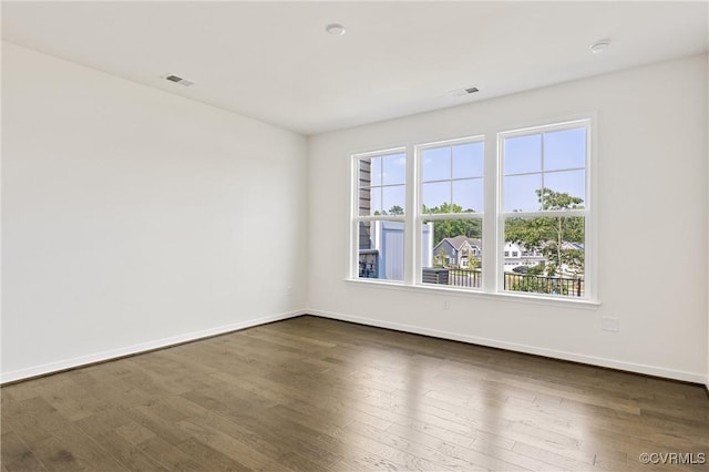 unfurnished room with dark wood-type flooring, baseboards, and visible vents