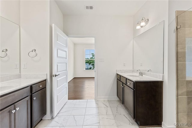 full bath featuring visible vents, baseboards, two vanities, marble finish floor, and a sink