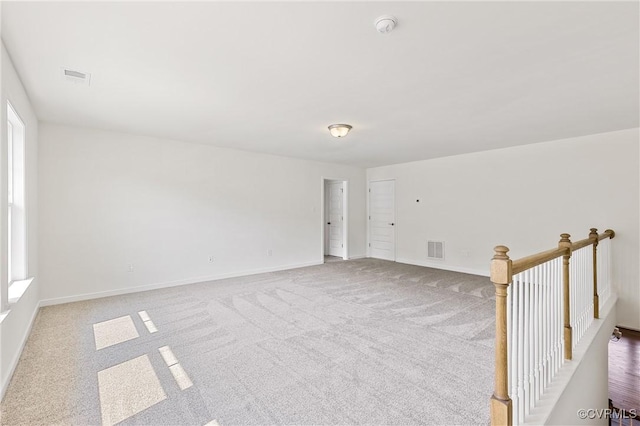 carpeted spare room with visible vents and baseboards