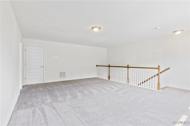 carpeted spare room with visible vents and baseboards