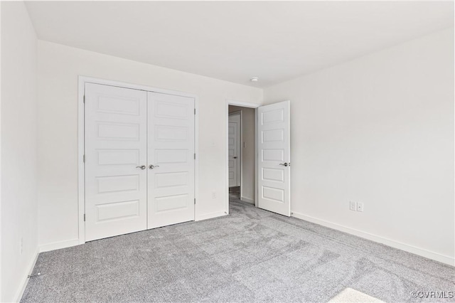 unfurnished bedroom featuring baseboards, carpet floors, and a closet