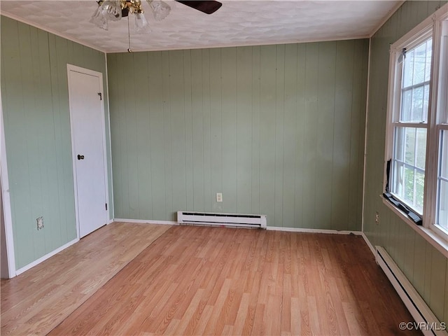 unfurnished room featuring light wood finished floors, a baseboard heating unit, and baseboards