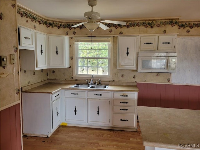 kitchen featuring light wood-style flooring, a sink, white cabinetry, white microwave, and ceiling fan