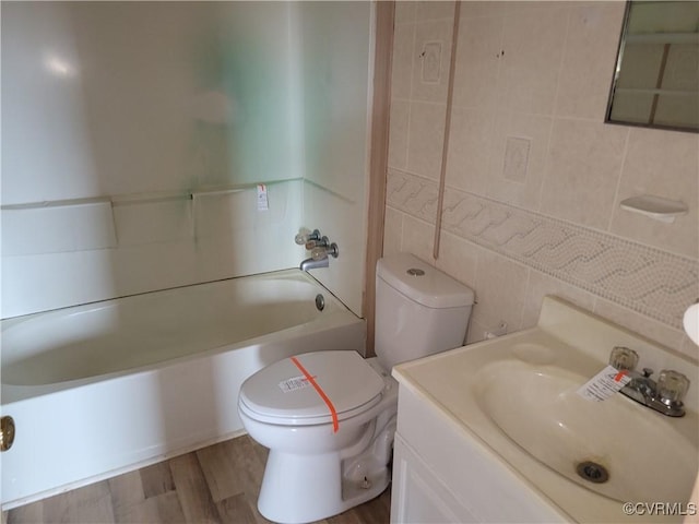 bathroom featuring toilet, wood finished floors, tile walls, shower / bath combination, and vanity