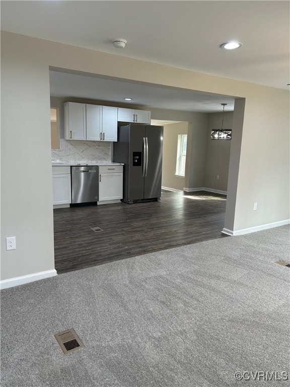 kitchen with visible vents, backsplash, dark carpet, appliances with stainless steel finishes, and white cabinetry