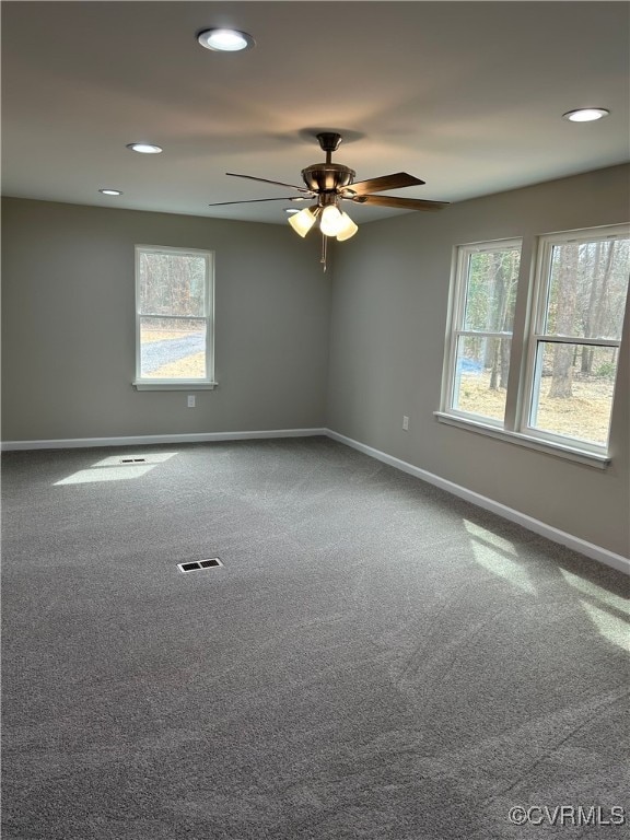 unfurnished room with visible vents, baseboards, plenty of natural light, and carpet floors