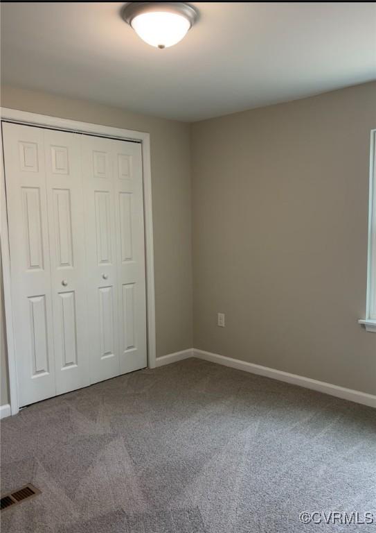 unfurnished bedroom with a closet, visible vents, baseboards, and carpet floors