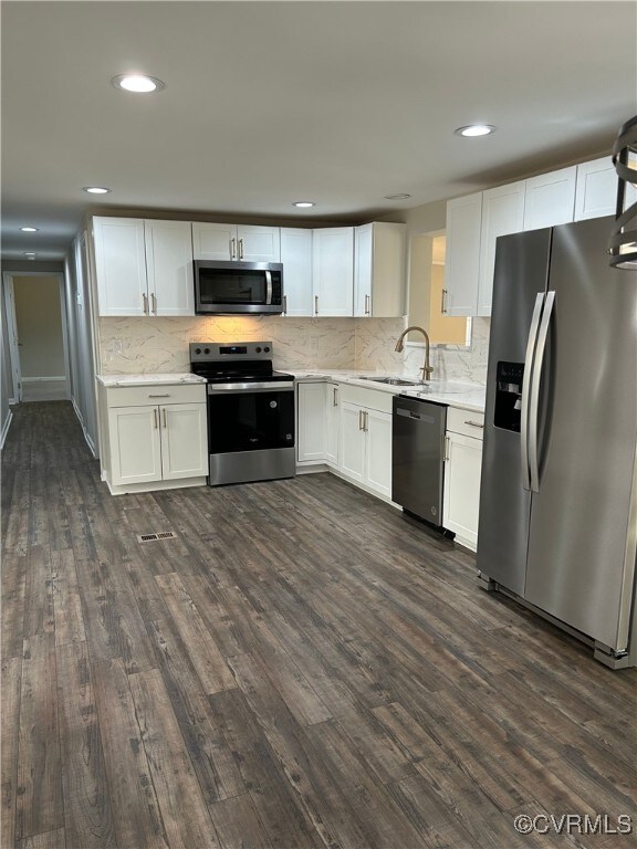 kitchen featuring dark wood finished floors, appliances with stainless steel finishes, white cabinetry, and a sink