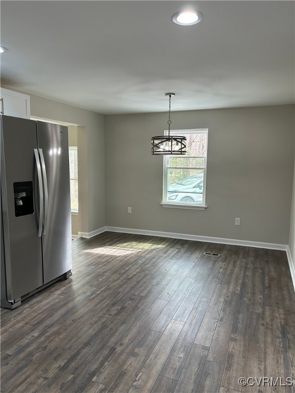 unfurnished dining area with plenty of natural light, dark wood-type flooring, and baseboards