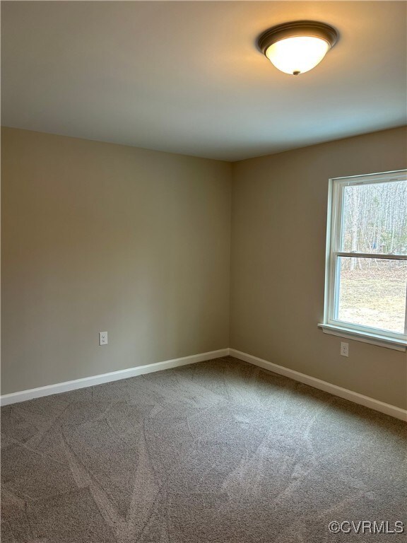 unfurnished room with carpet flooring and baseboards