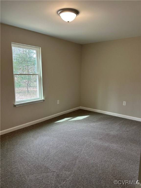 unfurnished room featuring baseboards and dark colored carpet