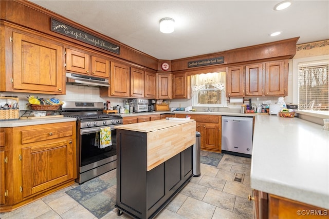 kitchen with under cabinet range hood, wood counters, plenty of natural light, and appliances with stainless steel finishes