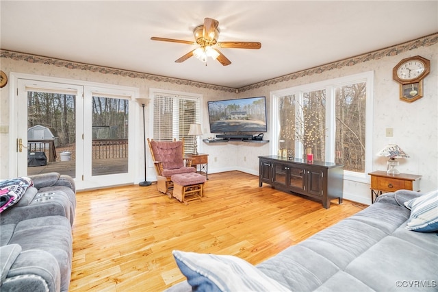 living area featuring baseboards, a healthy amount of sunlight, wallpapered walls, and light wood-style floors