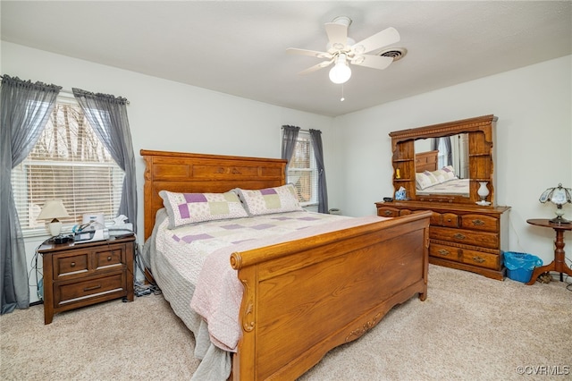 bedroom featuring visible vents, light colored carpet, and ceiling fan