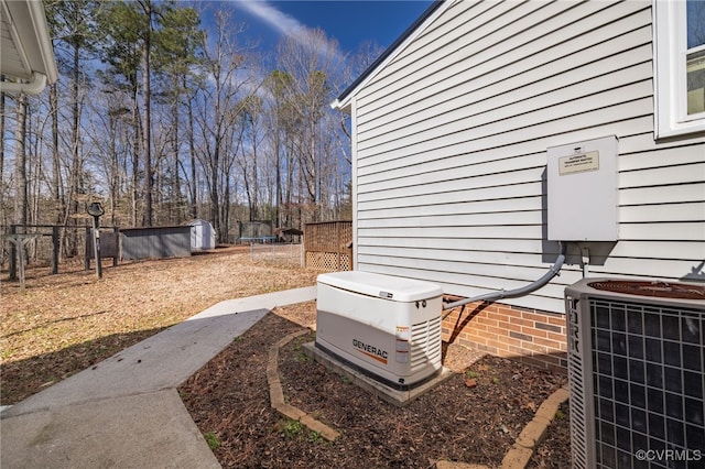 exterior space with an outbuilding, central air condition unit, a storage unit, and fence