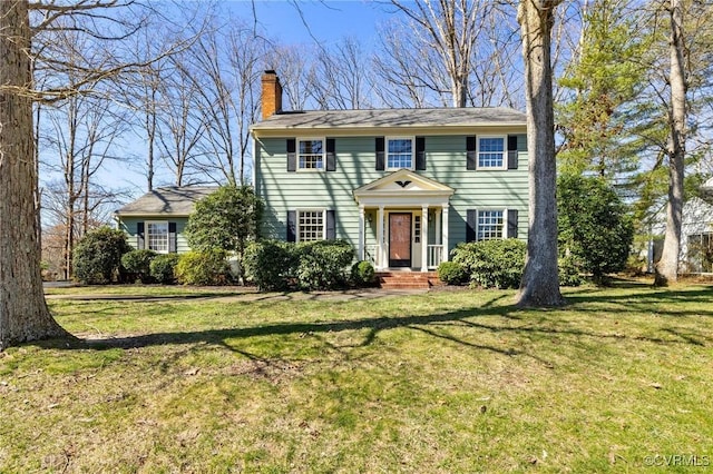 colonial-style house featuring a front lawn and a chimney