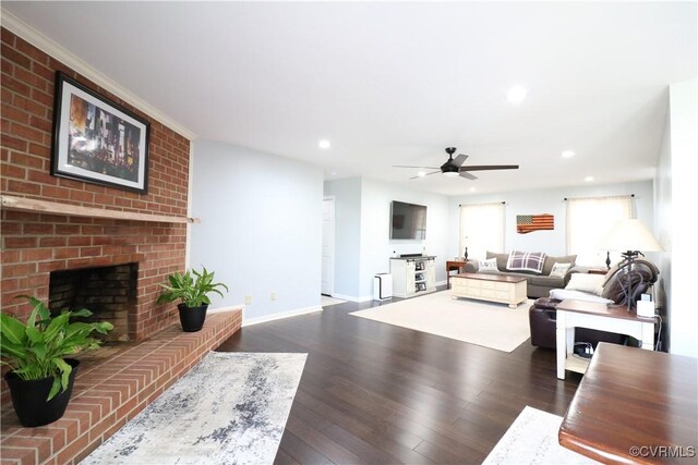 living area with dark wood-style floors, recessed lighting, a brick fireplace, and baseboards