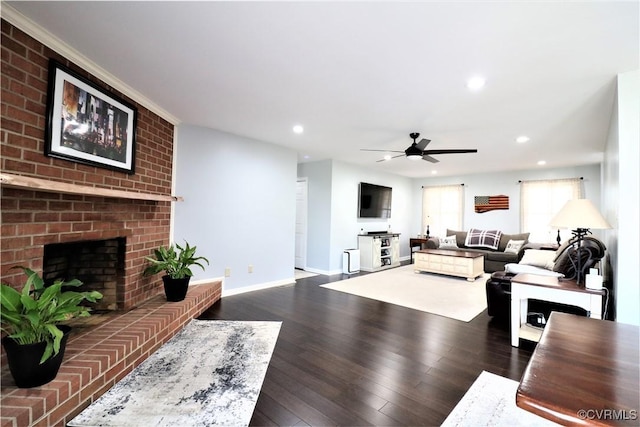 living room featuring a ceiling fan, hardwood / wood-style flooring, recessed lighting, baseboards, and a brick fireplace