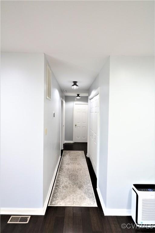 hall featuring dark wood finished floors, baseboards, and visible vents